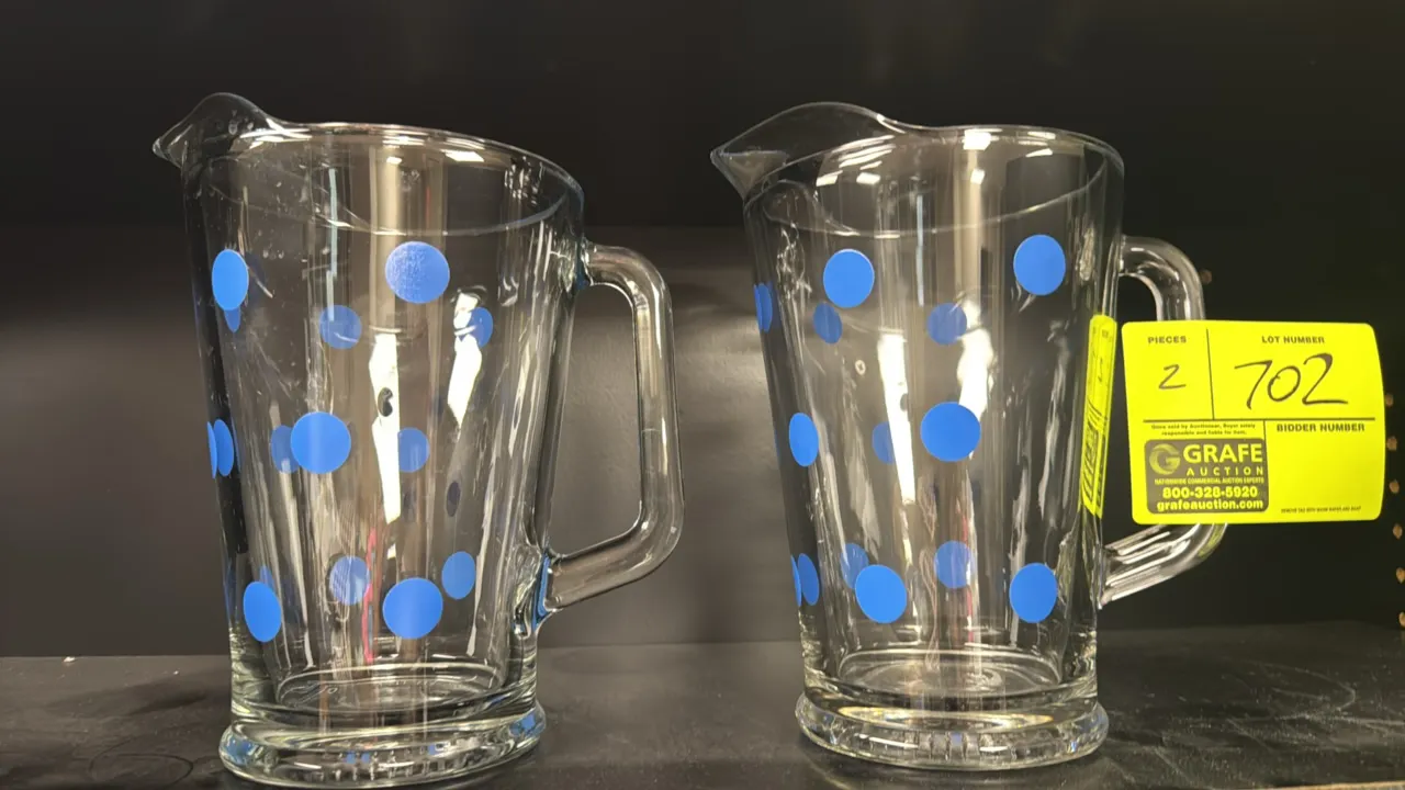 Decorative glass pitchers. Features clear glass construction with blue polka dot design, integrated pour spouts, side handles, and thick bases.