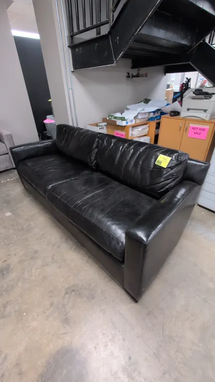 Coach leather cushioned sofa. Features black faux leather upholstery, 2-cushion seat design, plush pillow back cushions, and straight track arms. 81"L