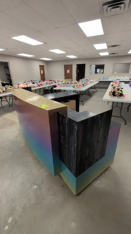 Laminate L-shaped reception desk. Features a bowed front transaction counter, rainbow gradient glitter finish, swirl-pattern work surface, 3-drawer st