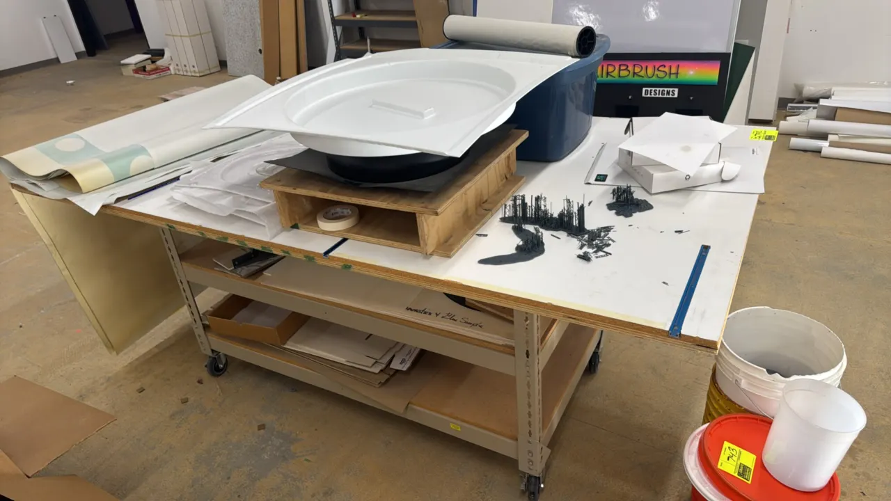 Multi-tier portable work table. Features a wood work surface, steel frame construction, and two lower shelves. Dimensions: 8' x 4'. Mounted on swivel