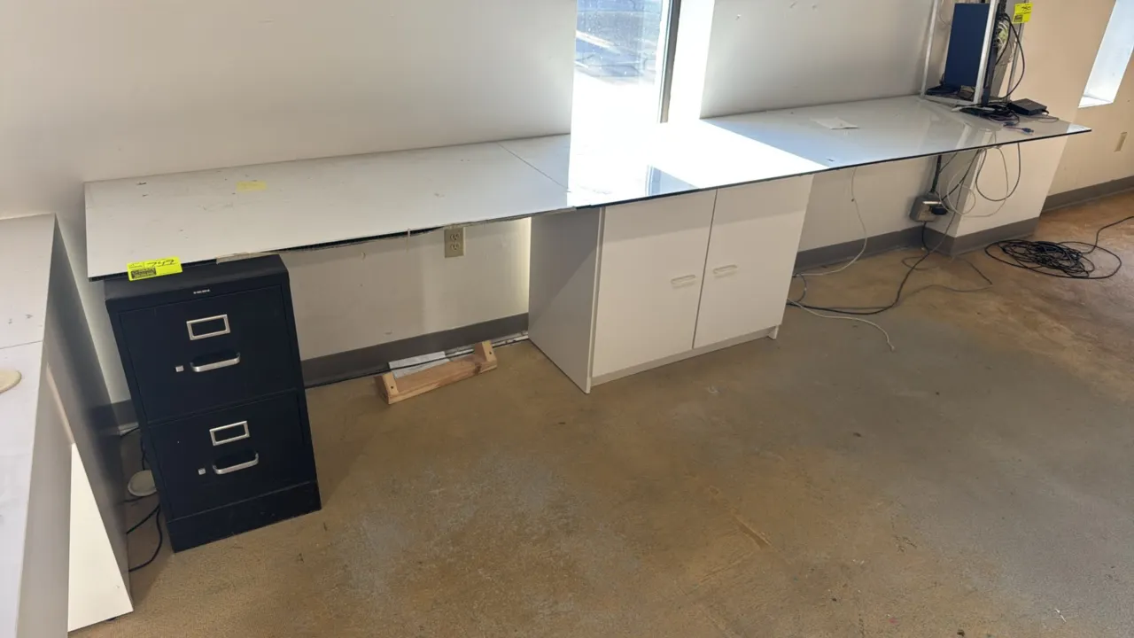 Custom work table. Features a white laminate work surface supported by a HON 2-drawer black metal file cabinet and a white 2-door base storage cabinet
