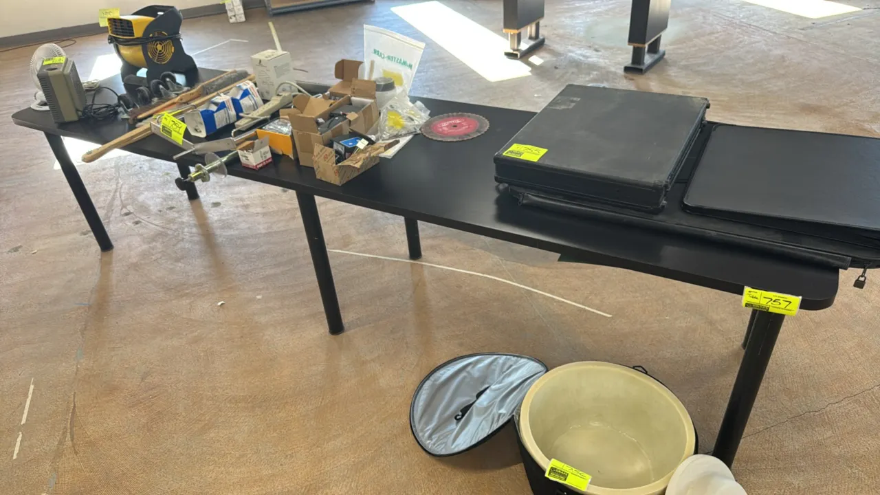 Laminate table. Features a black laminate tabletop with rounded corners and six black cylindrical metal post legs. Dimensions: 120"L x 30"W. Contents