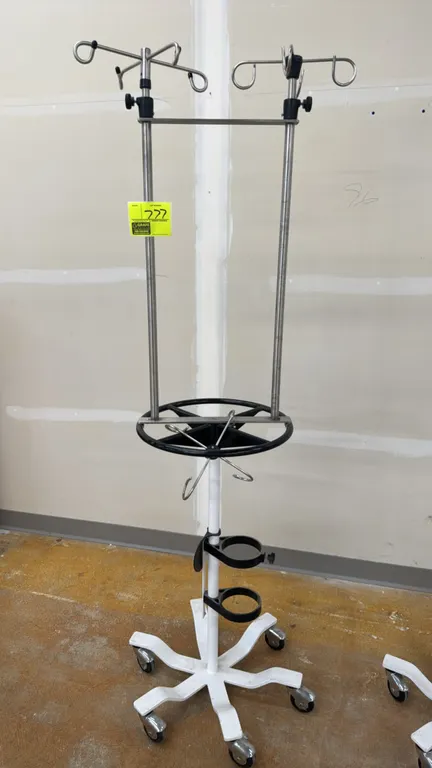 Mobile heavy-duty IV stand. Features dual adjustable uprights with IV bag hooks, circular steering handle, and lower oxygen cylinder holder bracket. 7