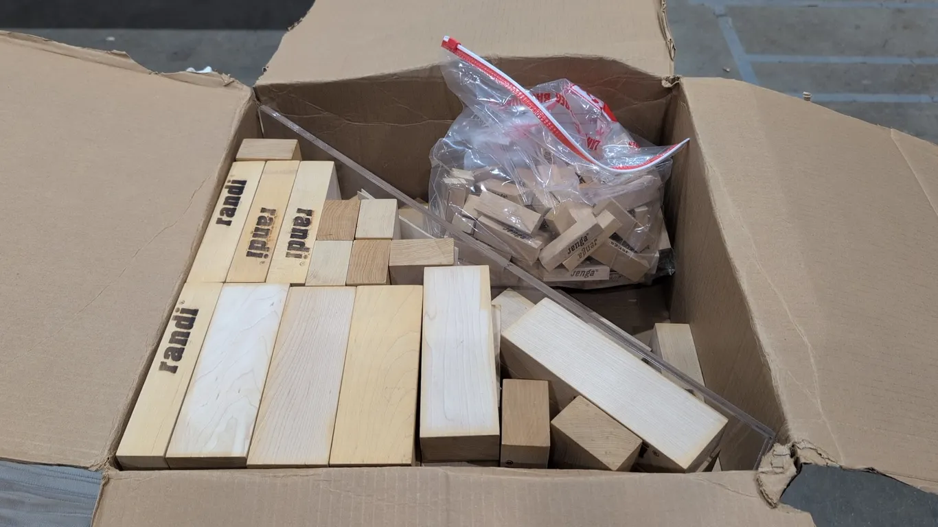 Assorted wooden block stacking game sets. Includes standard Jenga wooden blocks in a zip-top plastic bag and jumbo Randi solid wood stacking blocks wi