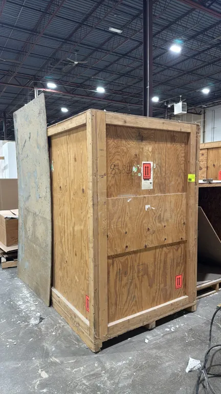 Wood shipping crate. Features plywood panel construction with dimensional lumber framing reinforcement and an integrated pallet skid base for forklift