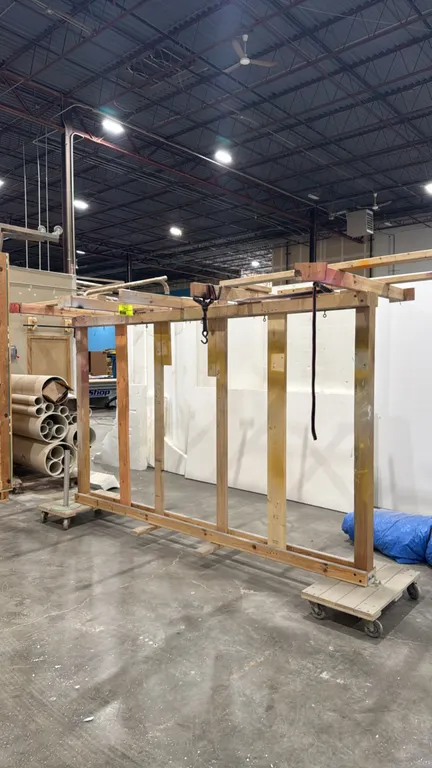 Custom wood painting and drying rack. Features dimensional lumber frame construction, upper cross supports with hanging hooks, and dual wheeled dolly