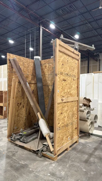 Assorted metal stock and caster base channels with wooden crate. Includes various steel angle, channel, and rectangular tubing stock, along with wheel