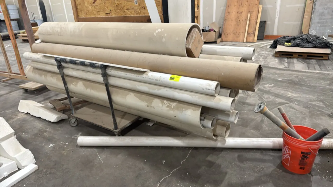 Assorted PVC pipe lot with mobile cart. Includes various diameters and lengths of rigid PVC pipe and heavy-duty cardboard tubes. Includes a rolling st