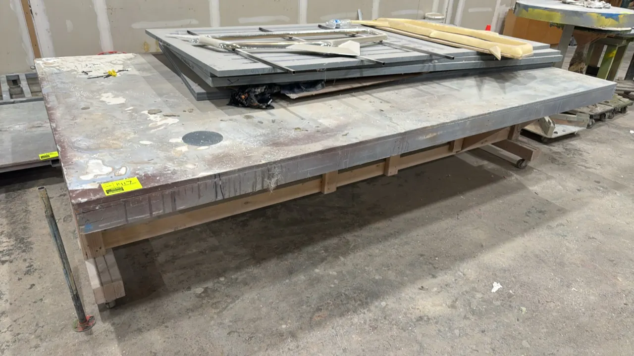 Portable wood work table. Features wood frame construction. Dimensions: 10'L x 6'W. Mounted on casters. Contents not included.