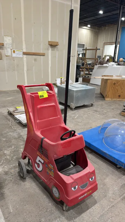 Smarte Carte Mall Racer children's mall stroller cart. Features molded red plastic race car body with #5 racing decals, child seat with safety lap str