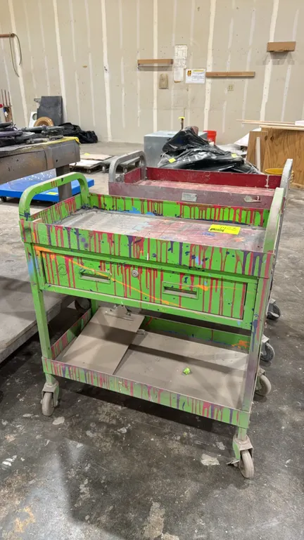 Metal work carts. Features top tray shelf, single drawer, lower open shelf, and integrated side handles. Dimensions: 30" x 16". Mounted on casters.