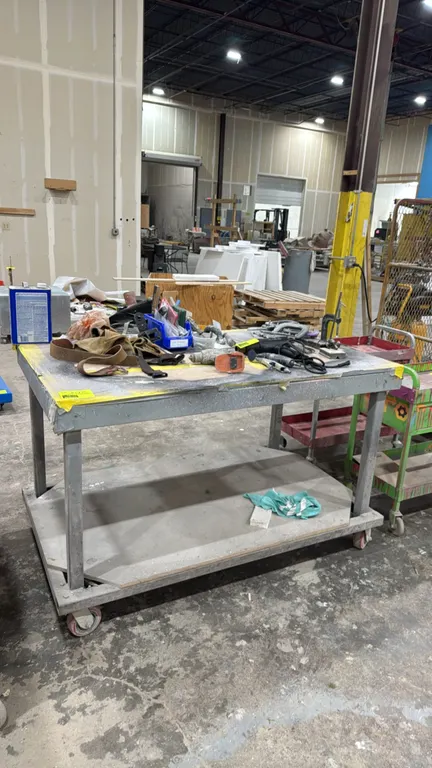 Metal portable workbench. Features wood top and lower wood undershelf. 5' x 3'. Mounted on casters. Contents not included.