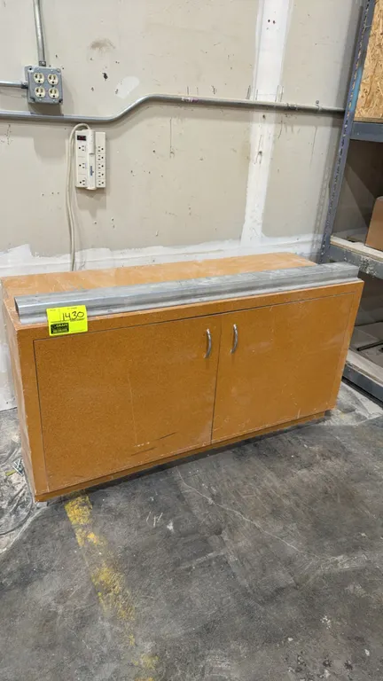 Wood 2-door storage cabinet. Features dual hinged doors with metal pull handles, interior shelving, and a top-mounted metal bumper rail. 49" x 17".