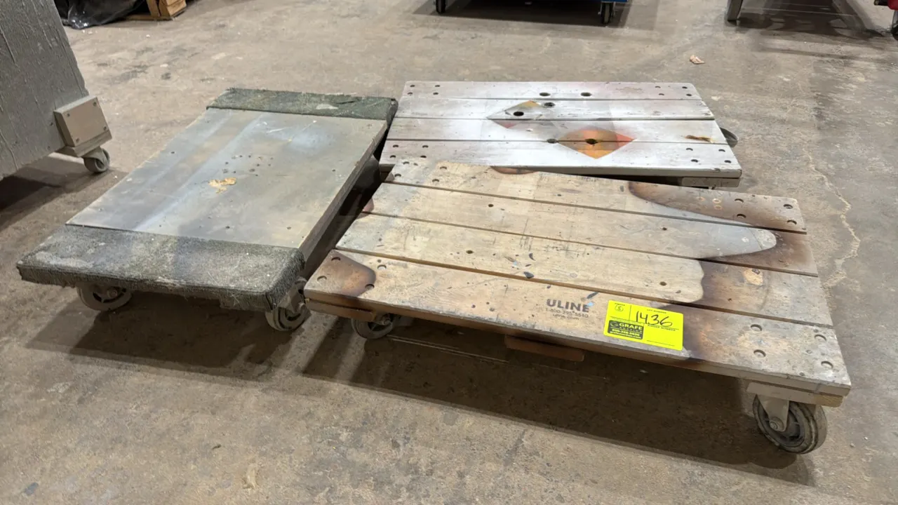 Assorted 4-wheel wood dollies. Includes (2) wood slat platform dollies (one marked Uline) and (1) solid deck dolly with carpeted ends. Each mounted on