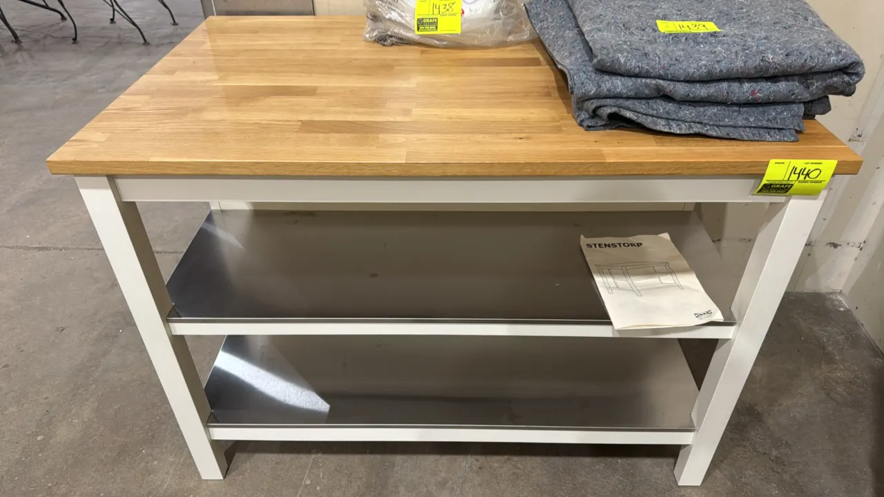 IKEA Stenstorp wood kitchen island table. Features a butcher block top, white frame, and (2) stainless steel covered undershelves. Includes assembly m