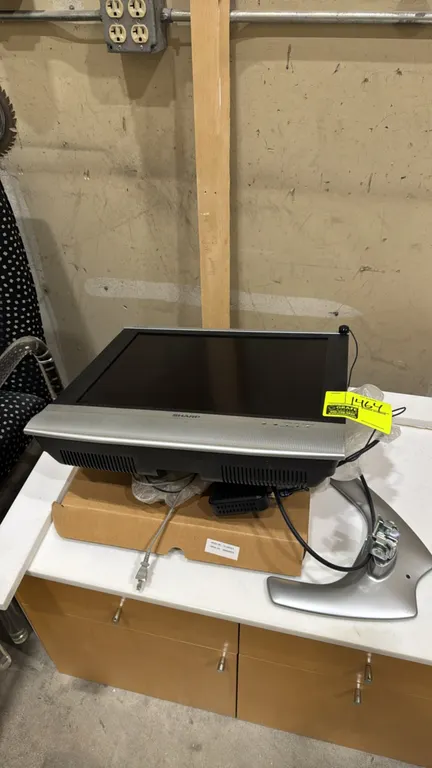 Sharp Aquos LC-20S4U-S LCD TV. Features front-firing stereo speakers and a black frame with silver-tone trim. Includes detached tabletop stand and ext