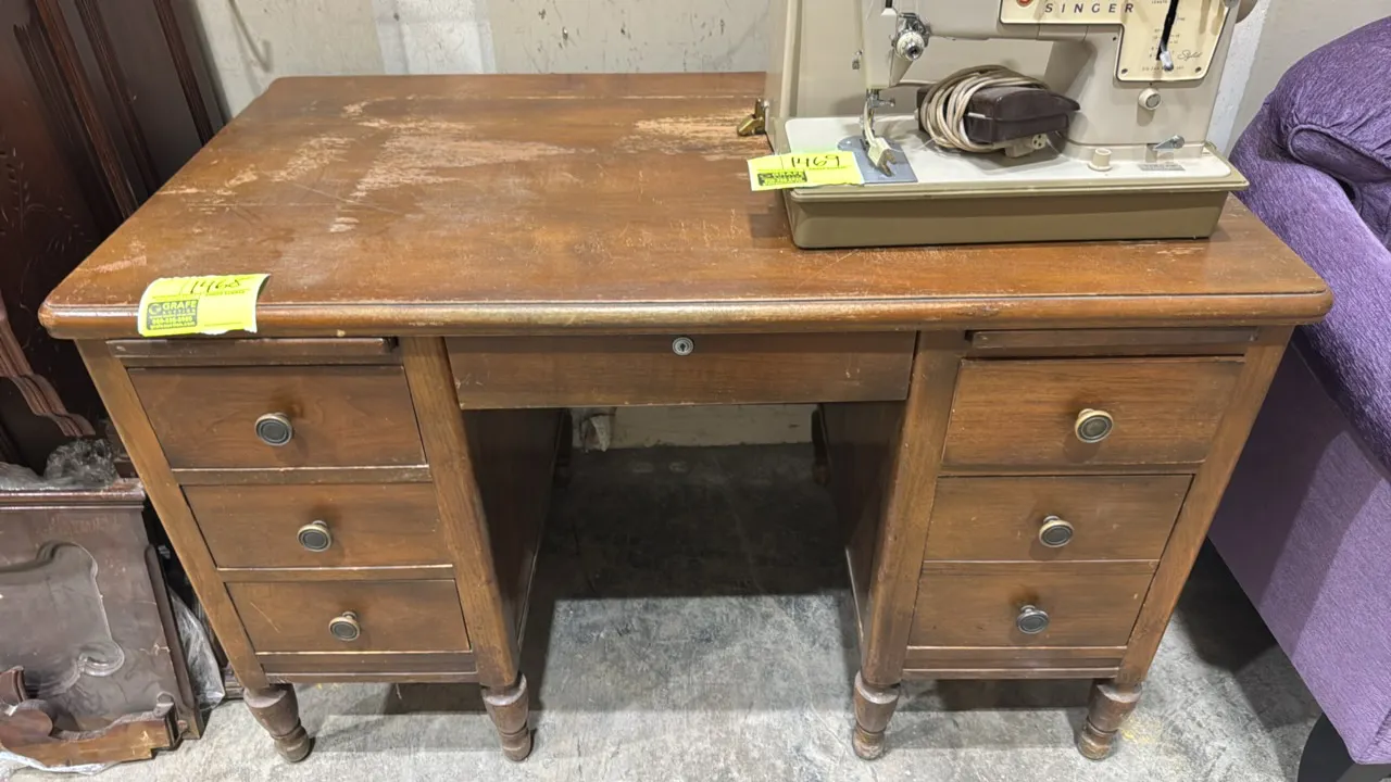 Vintage wood double-pedestal desk. Features seven drawers including a center drawer with built-in organizer tray, pull-out writing slides, round metal