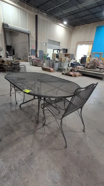Metal patio table with (2) armchairs. Features expanded metal mesh construction, oval tabletop with center umbrella hole, and curved legs. Chairs feat