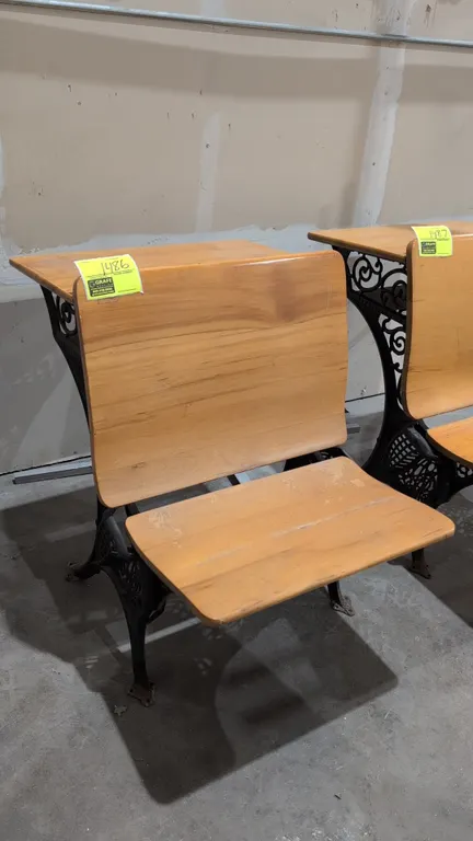 Vintage school desk. Features a wood top, folding wooden seat, under-desk book storage compartment, and ornate cast iron scrollwork frame with floor-m