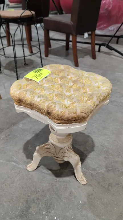 Vintage piano stool. Features a button-tufted cloth cushioned seat and painted finish. 19"H. Mounted on an ornate cast metal pedestal base with decora