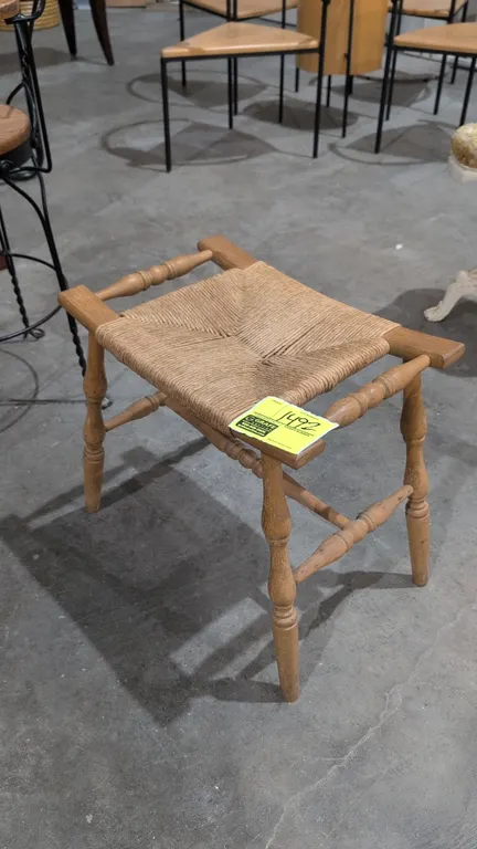 Wood stool with woven wicker seat. Features turned legs, spindle stretchers, and side handles. 18"H.