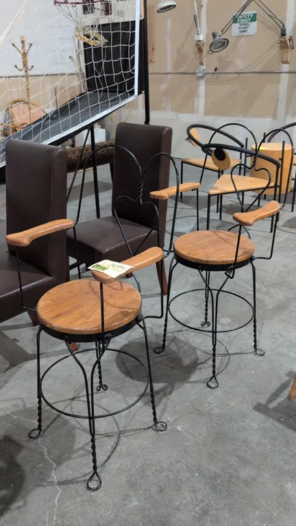 Wood and metal bar chairs. Features round wooden seats, wood armrest caps, sweetheart wire backrests, integrated circular footrest rings, and black tw