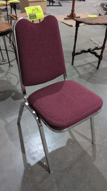 Upholstered banquet stacking chair. Features maroon fabric cushioned seat and backrest with integrated top hand hold. Mounted on a chrome-finish tubul