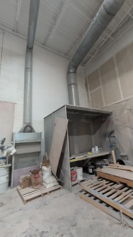 Industrial paint booth. Features overhead fluorescent lighting fixtures, rear exhaust filter wall, interior work bench, and exhaust ducting. Includes