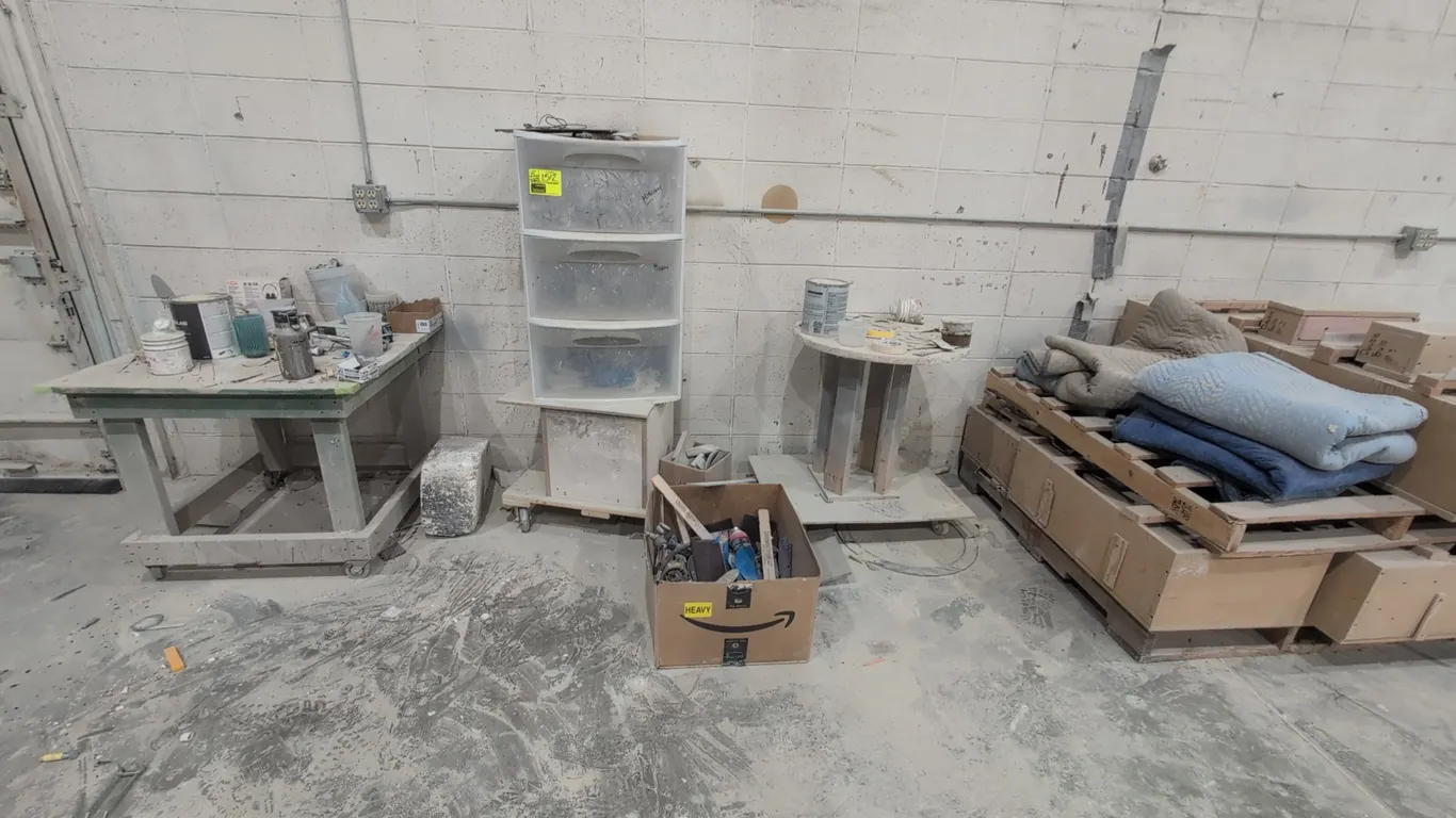 Workshop and studio contents against wall. Includes work tables, cut-out workbench, painted cabinet, 3-drawer plastic storage organizer on casters, pn