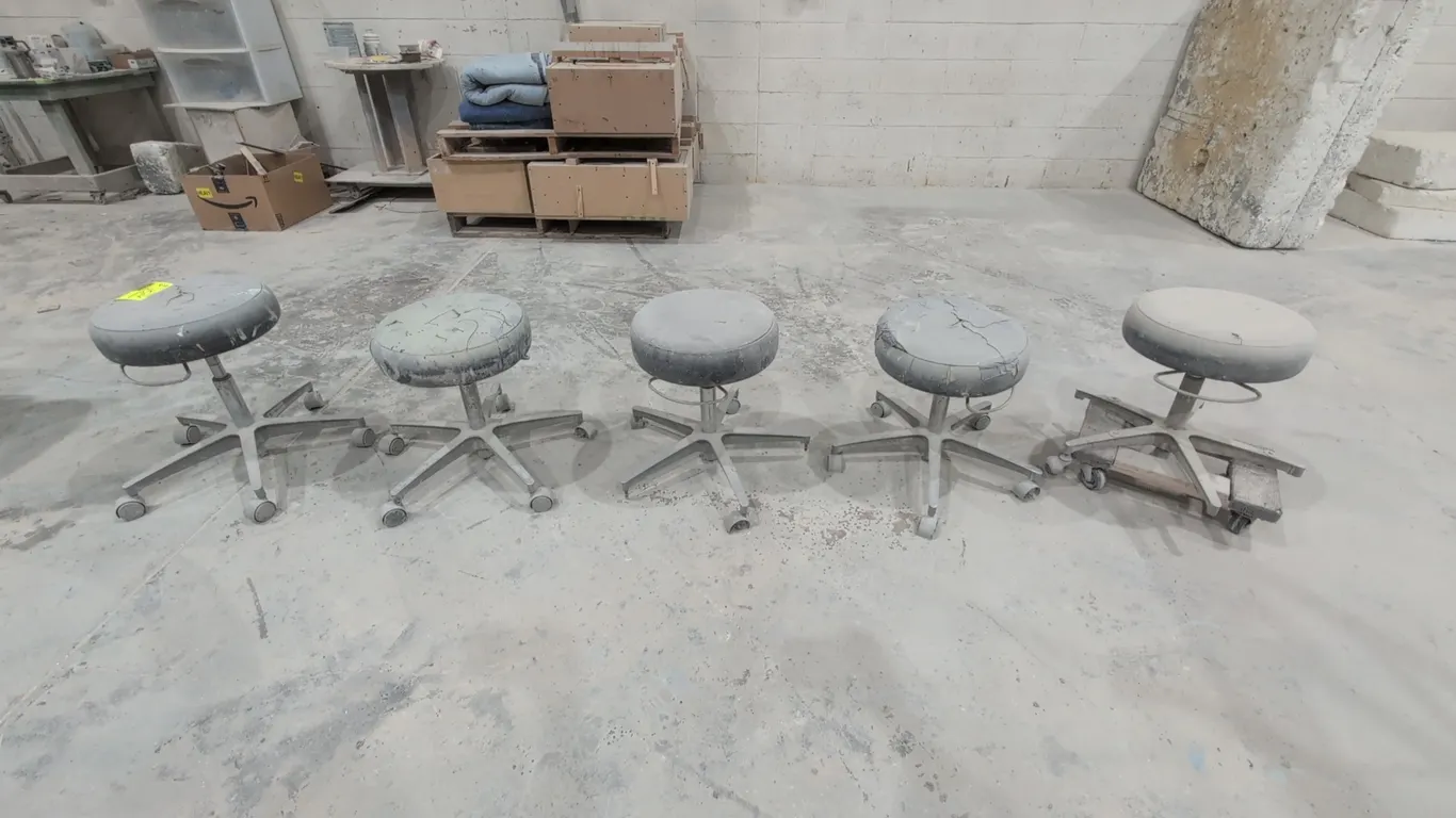 Assorted rolling shop stools. Features round padded upholstered seats, pneumatic height adjustment rings, and 5-star metal bases with swivel casters.