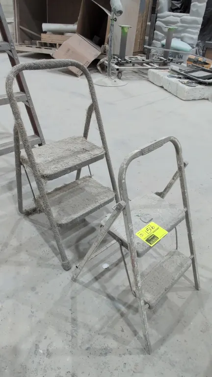 Assorted metal folding step stools. Includes (2) two-step folding step stools featuring tubular metal frames, dual steps, and integrated upper grab ha