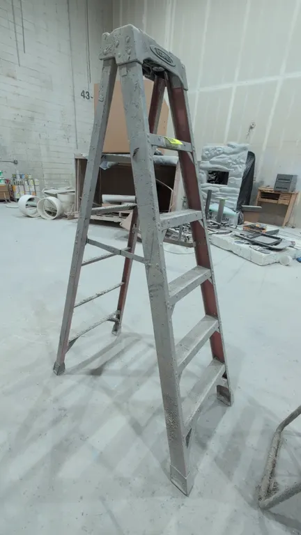 Werner 6' stepladder. Features fiberglass rails, 5 aluminum steps, molded top cap with tool slots, folding spreader braces, and slip-resistant feet. D