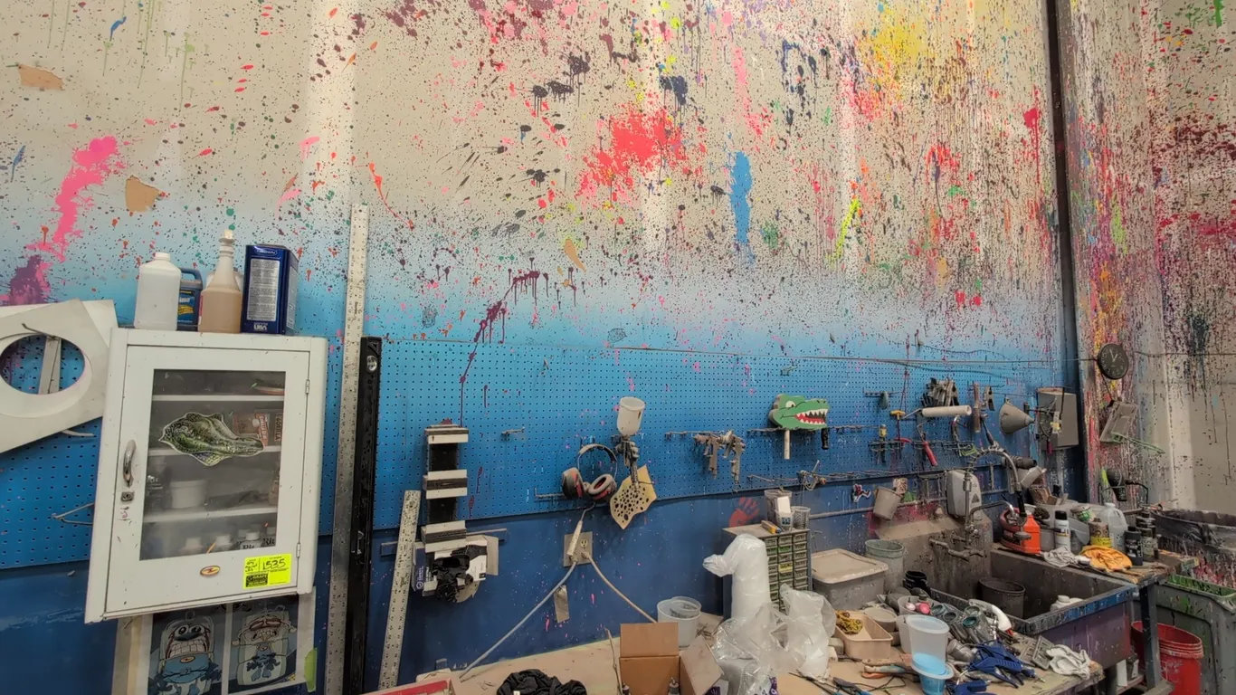 Assorted workshop wall merchandise lot. Includes a wall-mounted metal cabinet with viewing window, wall pegboard panels, faux brick display panels, sh