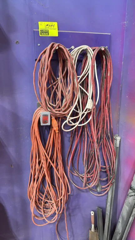 Assorted extension cords with wall-mount rack. Includes multiple extension cords in various lengths and colors. Features a wall-mounted organizer plat