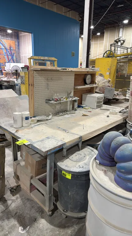 Custom portable work bench. Features a wood work surface on a steel frame, upper wooden hutch with pegboard, shelf, clock, tool rack with sculpting to