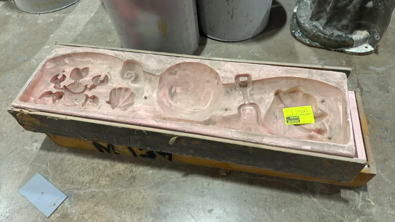 Beach-themed molds. Features pink flexible rubber or silicone molds encased in wooden support frames, depicting beach-themed relief motifs including a