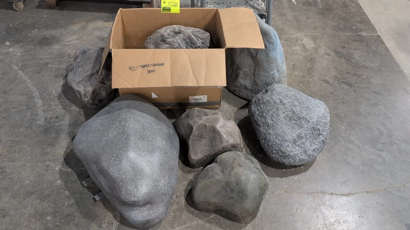 Assorted cast resin decorative rocks. Features varied shapes, sizes, and realistic stone textures with finishes including speckled, granite, smooth, a