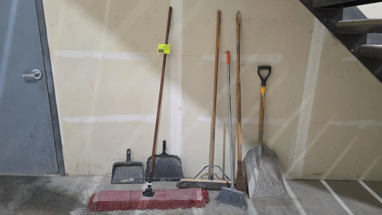Assorted cleaning and maintenance tools. Includes wide dry dust mop, push broom with support brace, angle broom, long-handled floor scraper, aluminum