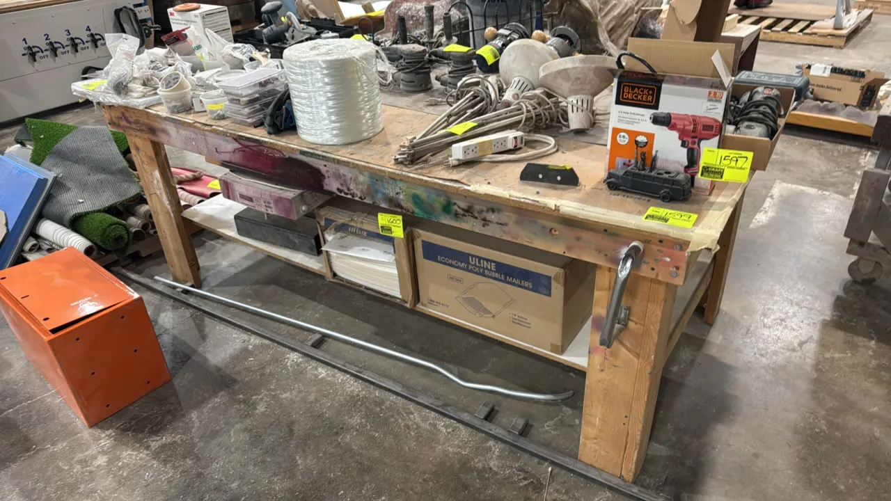 Custom wood workbench. Features solid wood construction, lower storage shelf, and side grab handle. Dimensions: 8'L x 4'W. Contents not included.