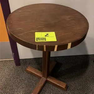 Round wood pedestal table. Features a circular top with decorative edge accents and a central column. 19"Dia. Mounted on a 4-point wood cross base.