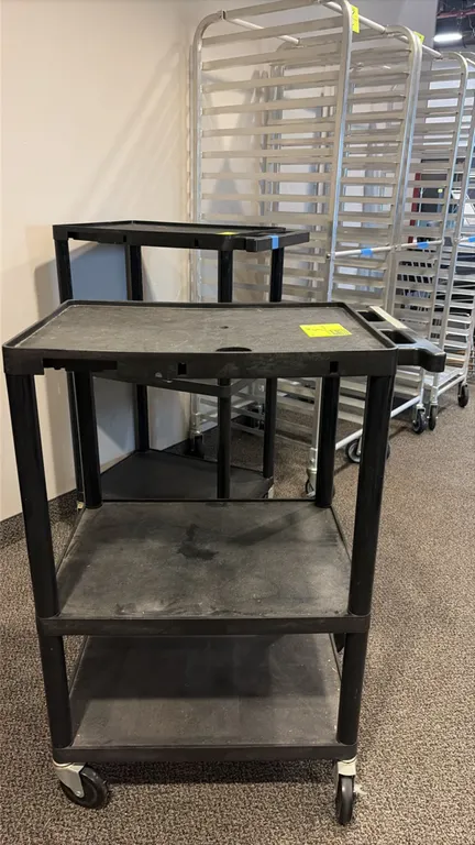 Polymer 3-tier portable utility cart. Molded black plastic construction featuring three shelves with retaining lip borders and integrated push handle.