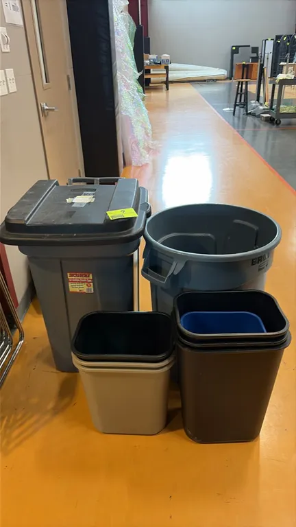 Assorted trash cans and wastebaskets. Includes Rubbermaid Roughneck wheeled trash can with lid, Rubbermaid Brute round container, and assorted nested