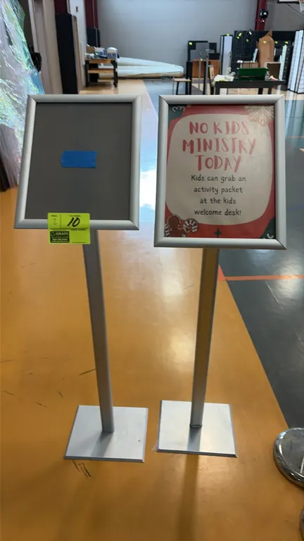 Aluminum sign stands. Features front-loading snap frames and vertical upright posts. Mounted on flat square bases. Sign insert not included.