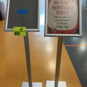 Aluminum sign stands. Features front-loading snap frames and vertical upright posts. Mounted on flat square bases. Sign insert not included.