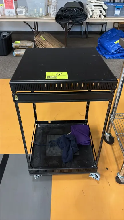 Metal equipment rack cart. Features an open-frame design with rack mounting rails, solid top surface, and lower shelf. 20" x 19". Mounted on swivel ca
