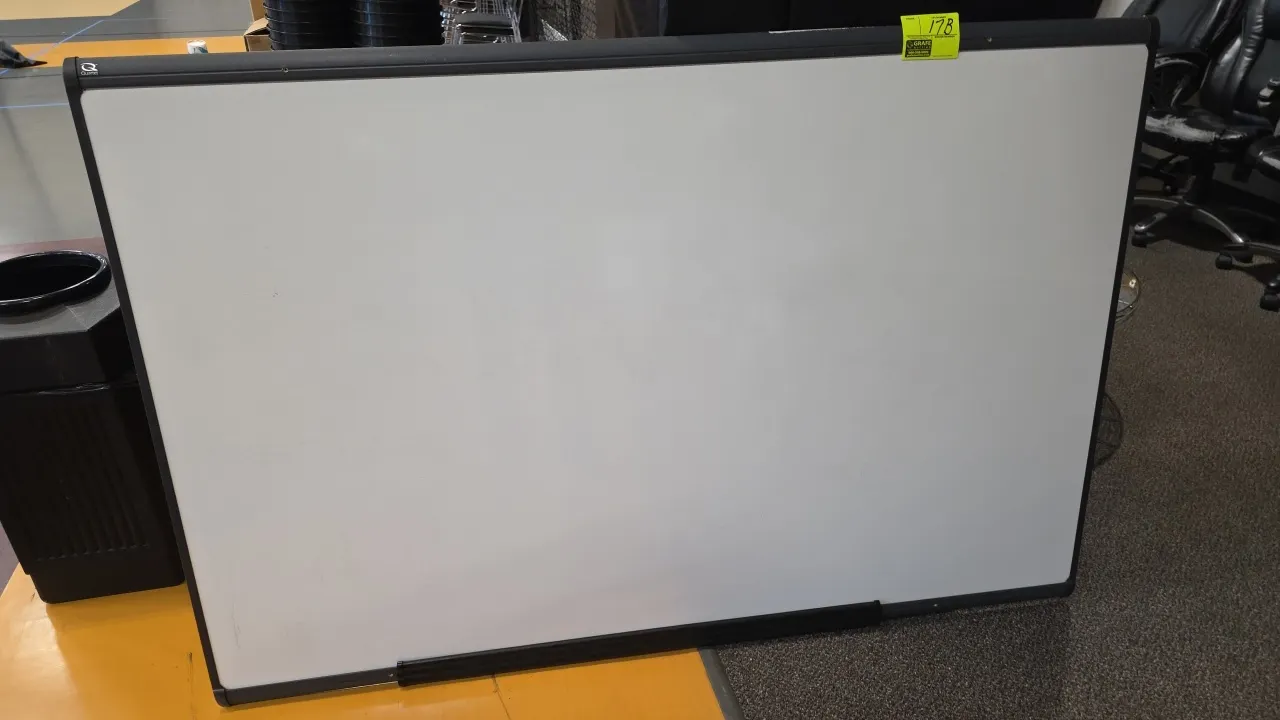 Quartet dry erase whiteboard. Features a dark gray frame and attached marker tray. Dimensions: 72"W x 48"H.