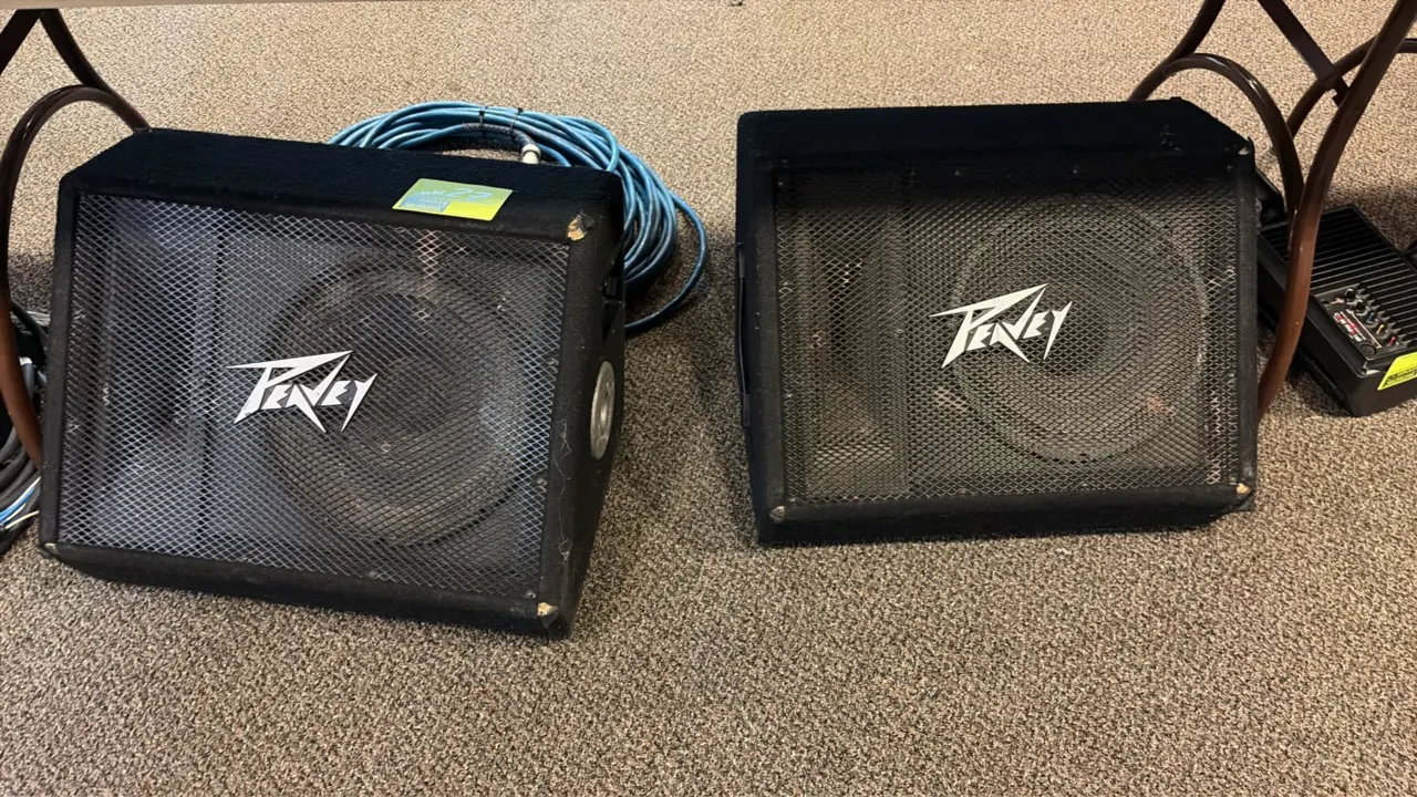 Peavey 112 Ti floor monitor speakers. Features angled wedge-style carpeted enclosures, metal mesh grilles, side carry handles, dual 1/4" jacks, and hi