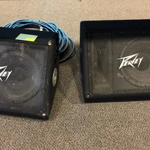 Peavey 112 Ti floor monitor speakers. Features angled wedge-style carpeted enclosures, metal mesh grilles, side carry handles, dual 1/4" jacks, and hi