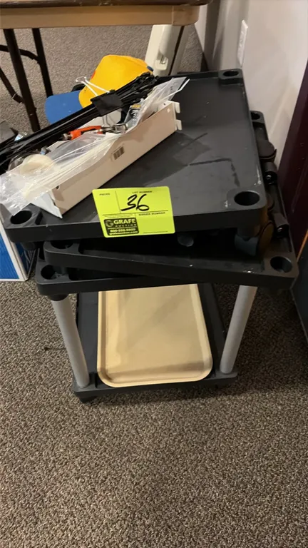 Plastic utility cart with assorted tools and parts. Features molded plastic shelving and swivel casters. Includes cable ties, hand tools, and assorted