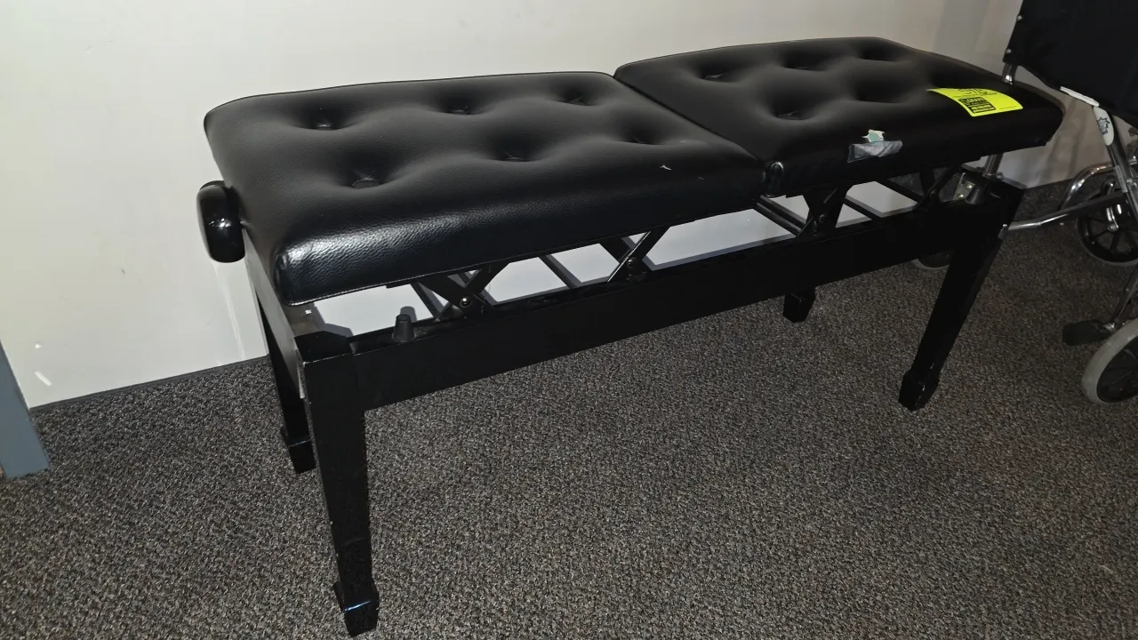 Adjustable height piano bench. Features dual adjustment knobs, split tufted padded seat cushions, and black metal frame. 40"L. Note: Upholstery has a